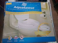 Front of boxed AquaSense raised toilet seat showing product image and branding
