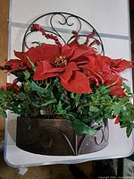 Front view of wall planter showing metal scroll frame and artificial poinsettias and foliage