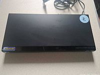 Top and partial front view of LG DV380H-N DVD player with power cord attached