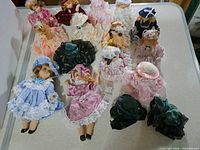 All fifteen porcelain dolls arranged on tabletop, showing variety of outfits and sizes