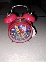 Front view of red M&M's twin bell alarm clock showing dial and bells