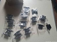 All 12 individually bagged black cabinet hinges on tabletop