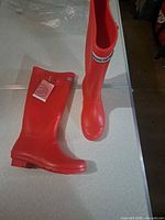 Full view of both red knee-high rain boots standing upright