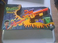 Front of boxed Glungies Slime Blaster set showing blaster, slime cup, figures, packaging damage