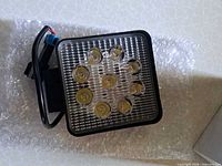 Front view of square LED light showing 9 LEDs and lens