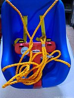 Front view of blue bucket swing showing T-bar, safety straps and rope