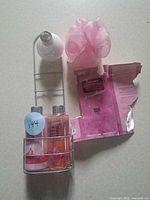 Full set: two bottles in metal caddy, pink pouf, torn package backing