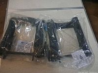 Two sealed black metal face cradle frames in plastic bags