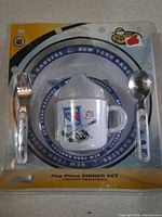 Front of sealed package showing plate rim, sippy cup, fork and spoon