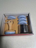 Box opened showing wooden handle, four blue stamp heads, metal cutter