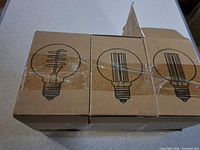 Three sealed cardboard boxes showing bulb icons
