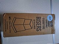 Sealed box showing product illustration and text "Adjustable Furniture Risers Set of 8 Piece"