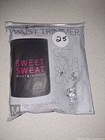 Front view of sealed retail bag showing Sweet Sweat waist trimmer label and medium size