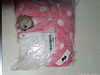 Factory-sealed pink polka dot romper in bag showing bear motif