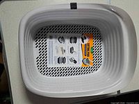 Top view of white sifter insert with instruction sheet inside black base