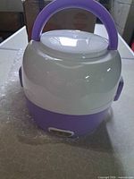 Front view of purple and white electric lunch box with handle