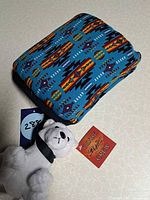 Plush bear and front of blue patterned pouch with tags visible