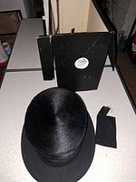 Overhead view of black felt top hat with hat box and separate ribbon