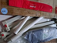 Disassembled white metal bed rail parts with red Playkids fabric piece