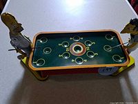 Full view of game showing both character figures, playfield and support legs