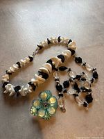 All items laid out: two necklaces and flower brooch
