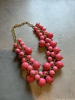 Full view of pink bauble necklace laid flat