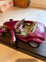 Top angled view of metallic purple Plymouth Prowler die-cast model with doors open on black base