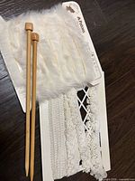 Overview showing wooden knitting needles, Patons faux fur trim card, and card with multiple white lace trims