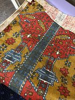 Close view of fabric showing red, mustard and blue Persian-style motif and weave