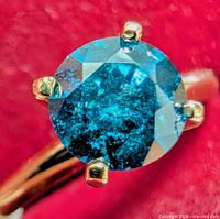 Top view of round blue diamond in 4-prong yellow gold setting