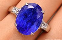 Ring on finger showing oval violet-blue tanzanite and diamond accents