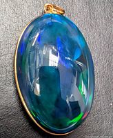 Front view of oval opal pendant showing play-of-color and gold bezel