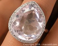 Pear-shaped kunzite ring on finger showing stone clarity and diamond halo