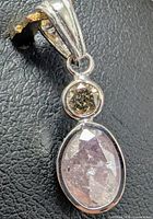 Front view of pendant showing pink oval diamond and brown round diamond in white gold setting