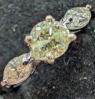 Close-up of three-stone diamond ring showing center round diamond and marquise side stones