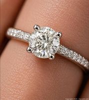 Close-up of ring on finger showing center diamond and accent stones