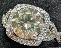 Close-up of ring showing round center diamond, halo, and prongs