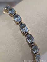 Close view of bracelet segment showing oval blue topaz and diamond separators
