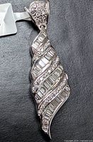 Front view of pendant showing swirl design and diamond setting