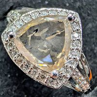 Top view of platinum ring showing center triangular diamond and surrounding halo of accent diamonds