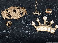 Group shot of both belt buckles, two rings, crown necklace