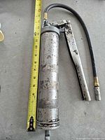 Full view grease gun alongside measuring tape showing 12 inch barrel