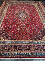 Full view of hand-knotted Kashan rug showing red field, medallion, borders, fringe