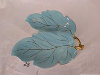 Top view of turquoise ceramic double-leaf dish showing gold painted veins and stem