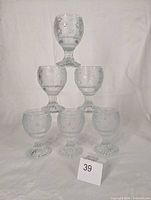 Six clear pressed glass goblets stacked to show pattern, quantity and uniformity