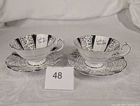 Two teacups on saucers showing front and interior inscription