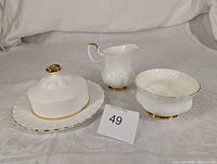 Creamer, sugar bowl, covered butter dish arranged on cloth