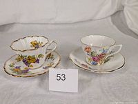Both teacup and saucer sets front view with lot tag