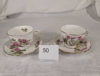 Front view of both teacup-and-saucer sets displaying patterns and gold trim