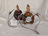 Two decorative horsehair flasks, braided straps visible